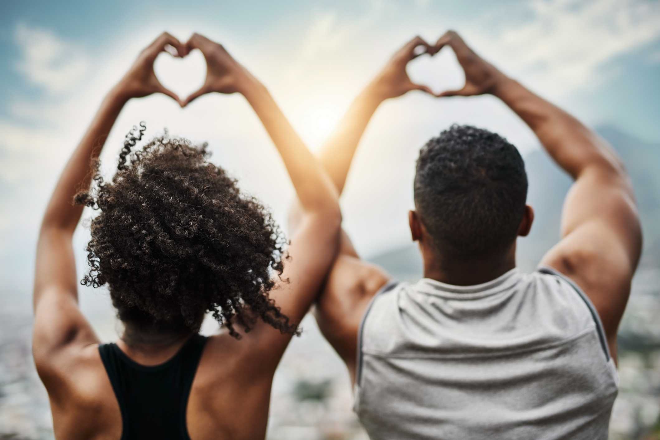 Rearview shot of a sporty young couple making heart shapes with their hands while exercising outdoors